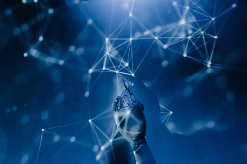 IMG_1694 A robotic hand reaching into a digital network on a blue background, symbolizing AI technology.
