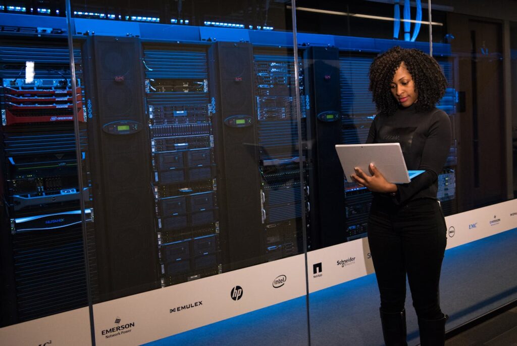 IMG_1695 A female engineer using a laptop while monitoring data servers in a modern server room.